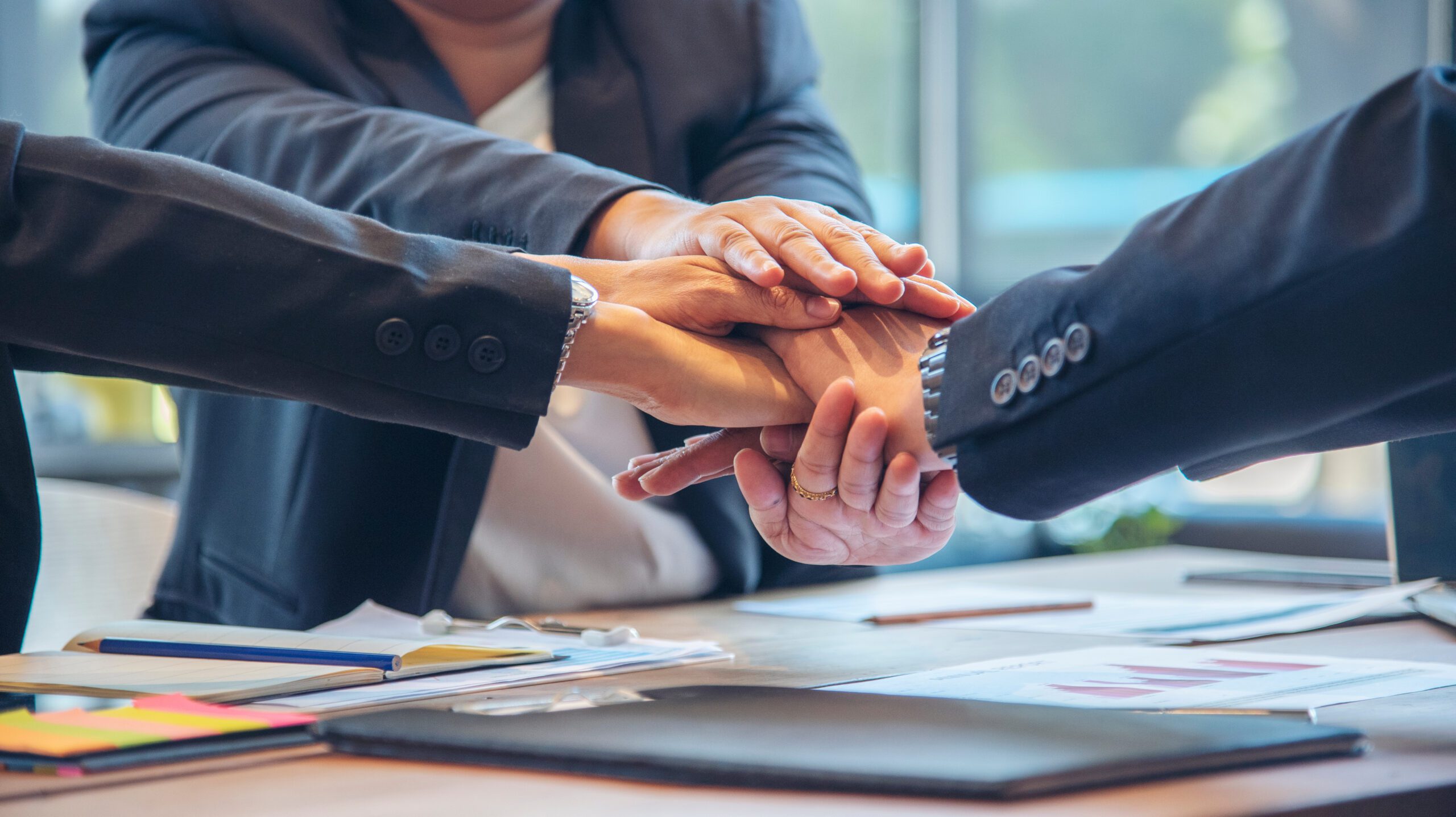 Business people with hands together over conference table